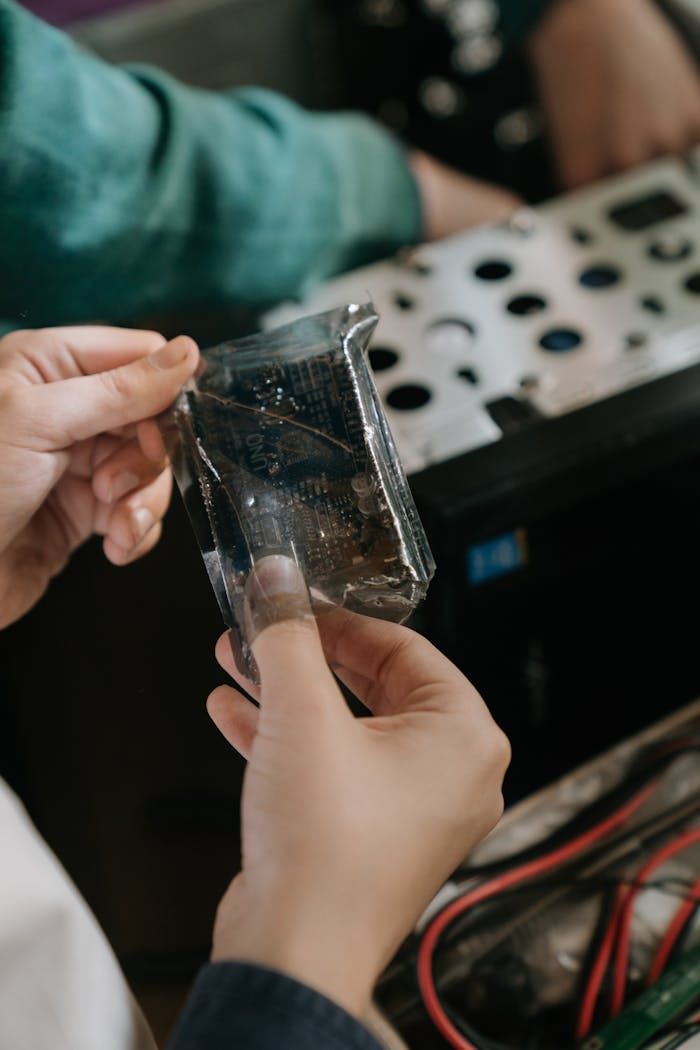 Close-up of hands holding a microchip in a computer repair setting.